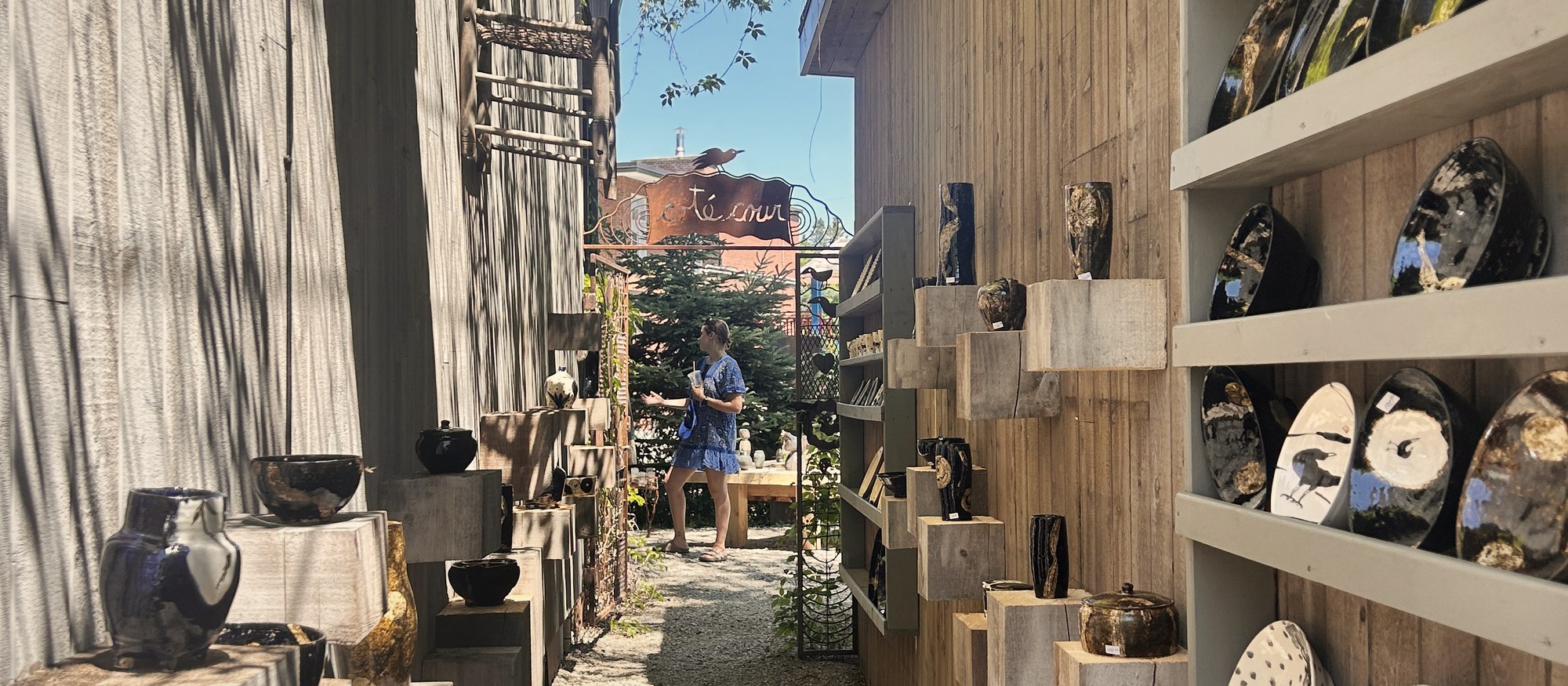 Des céramiques noires et dorées sur des étagères de bois à 1001 Pots, à Val-David