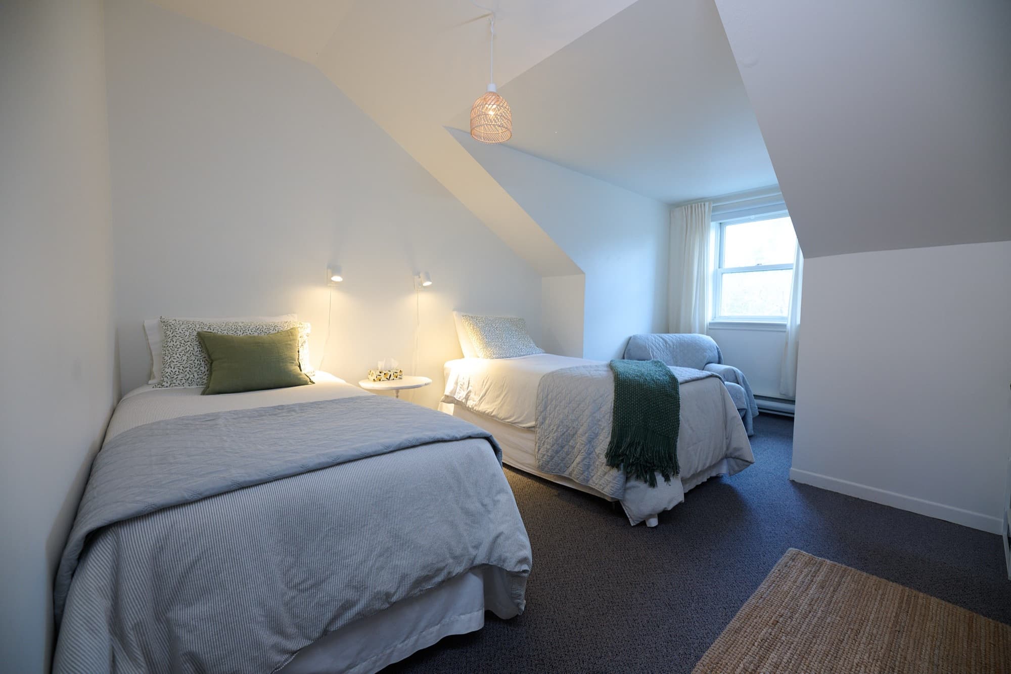 Attic room with two single beds, an armchair and a woven rug