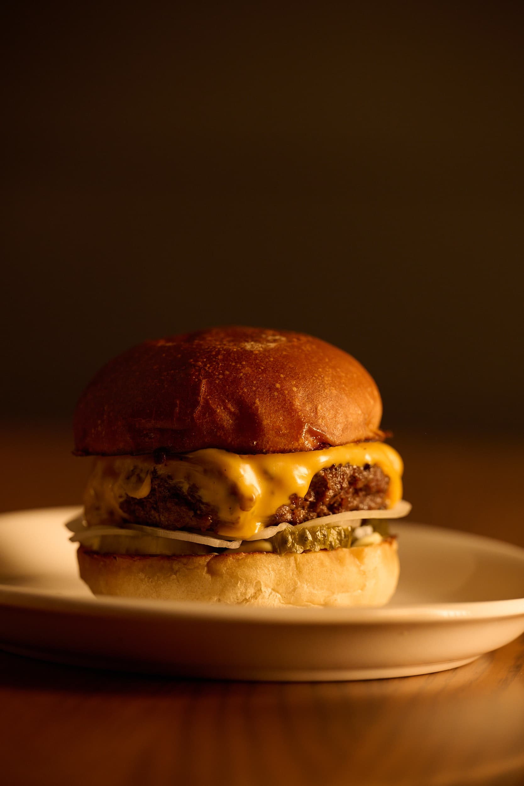 MacTaverne's burger: a thick local-beef patty, melting cheese, on a golden Boulangerie Graintitude bun, lit by candlelight