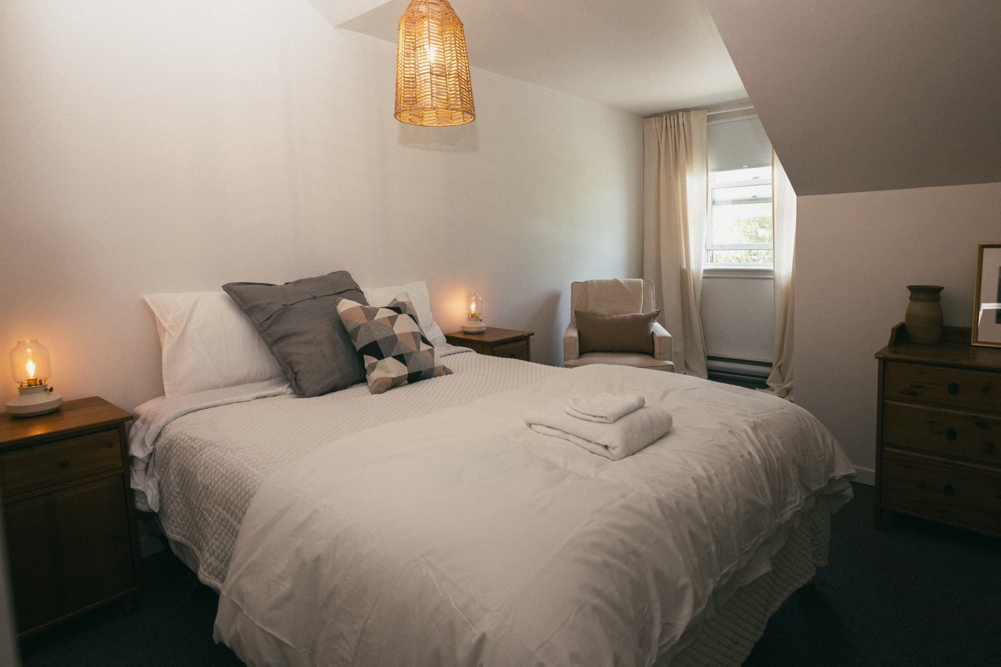 A MacTaverne auberge room upstairs above the pub, queen bed, warm evening light, in Val-David